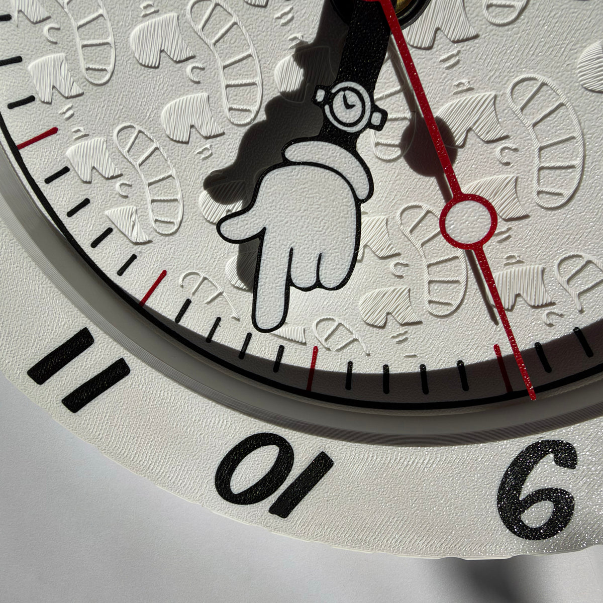 Close-up of a white textured clock face featuring a black cartoon hand pointing down, black numerals, and a red second hand.
