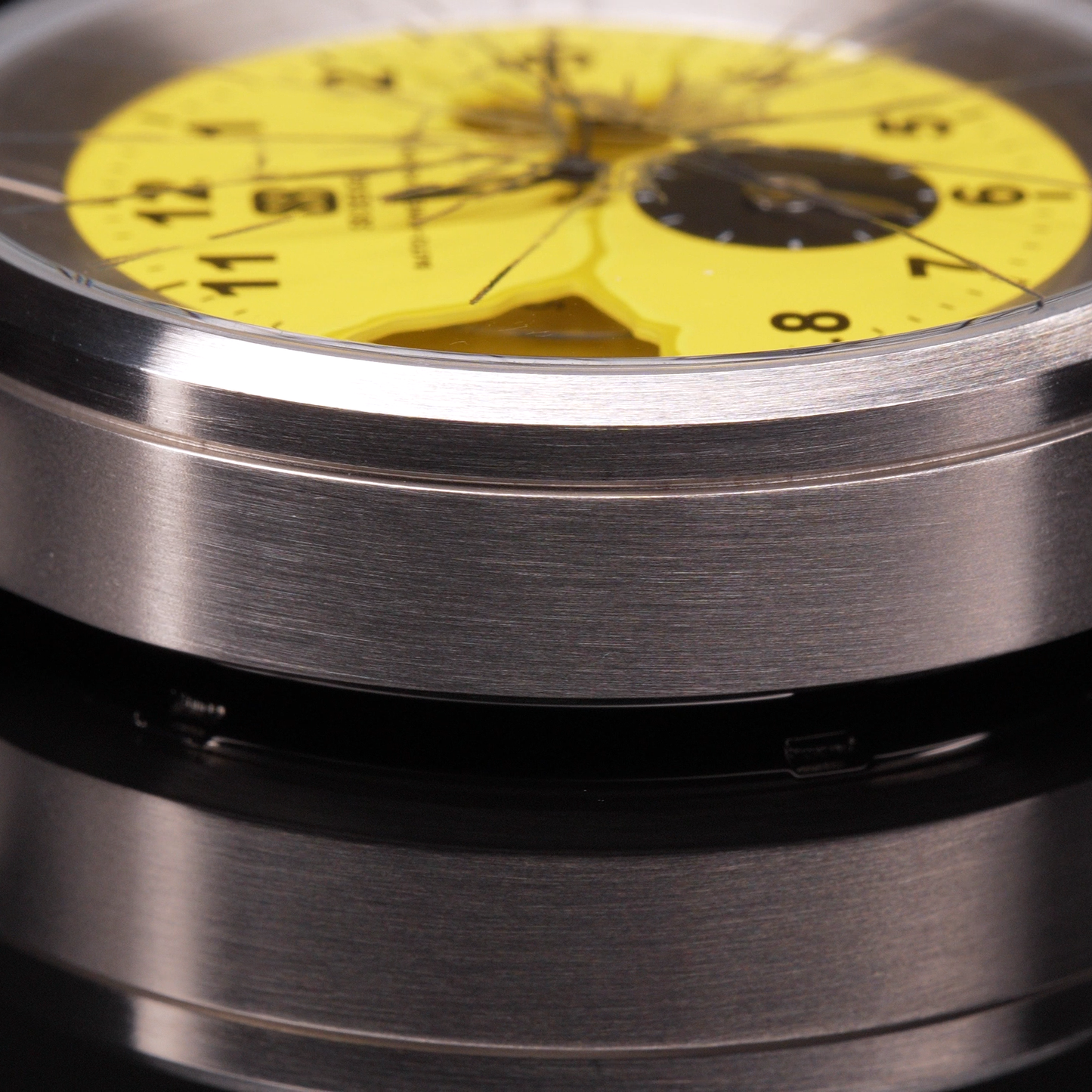 Wristwatch with yellow dial  and black numbers glass painted to look as if it is cracked and a stainless steel case on a black background Broken Time Watch Brad Podray Mad Hudson