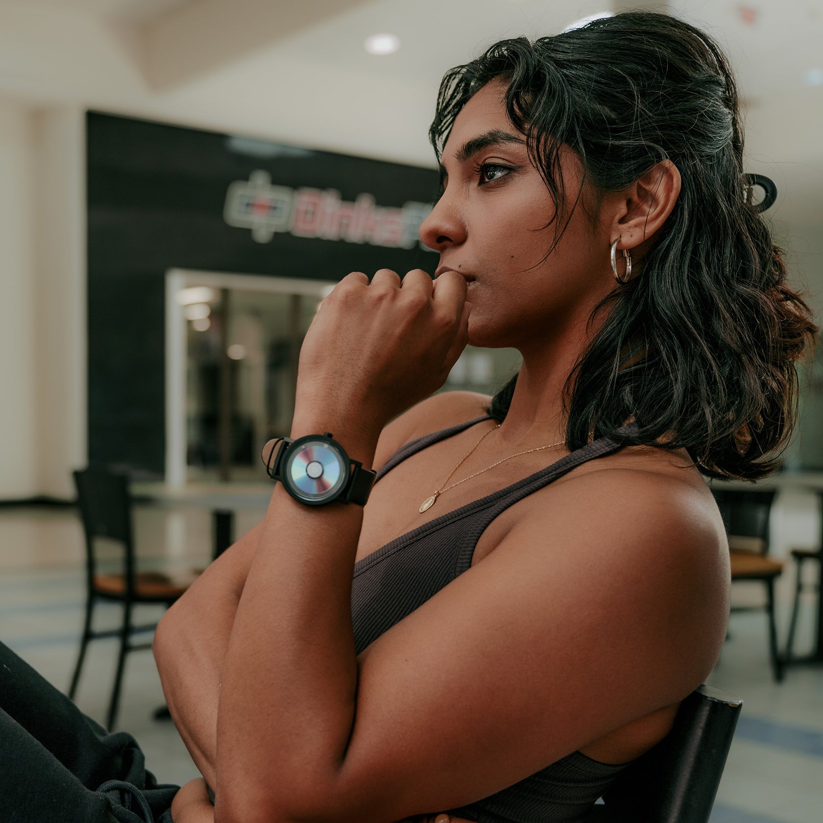 Woman sitting in a chair with a watch on her wrist in an indoor setting