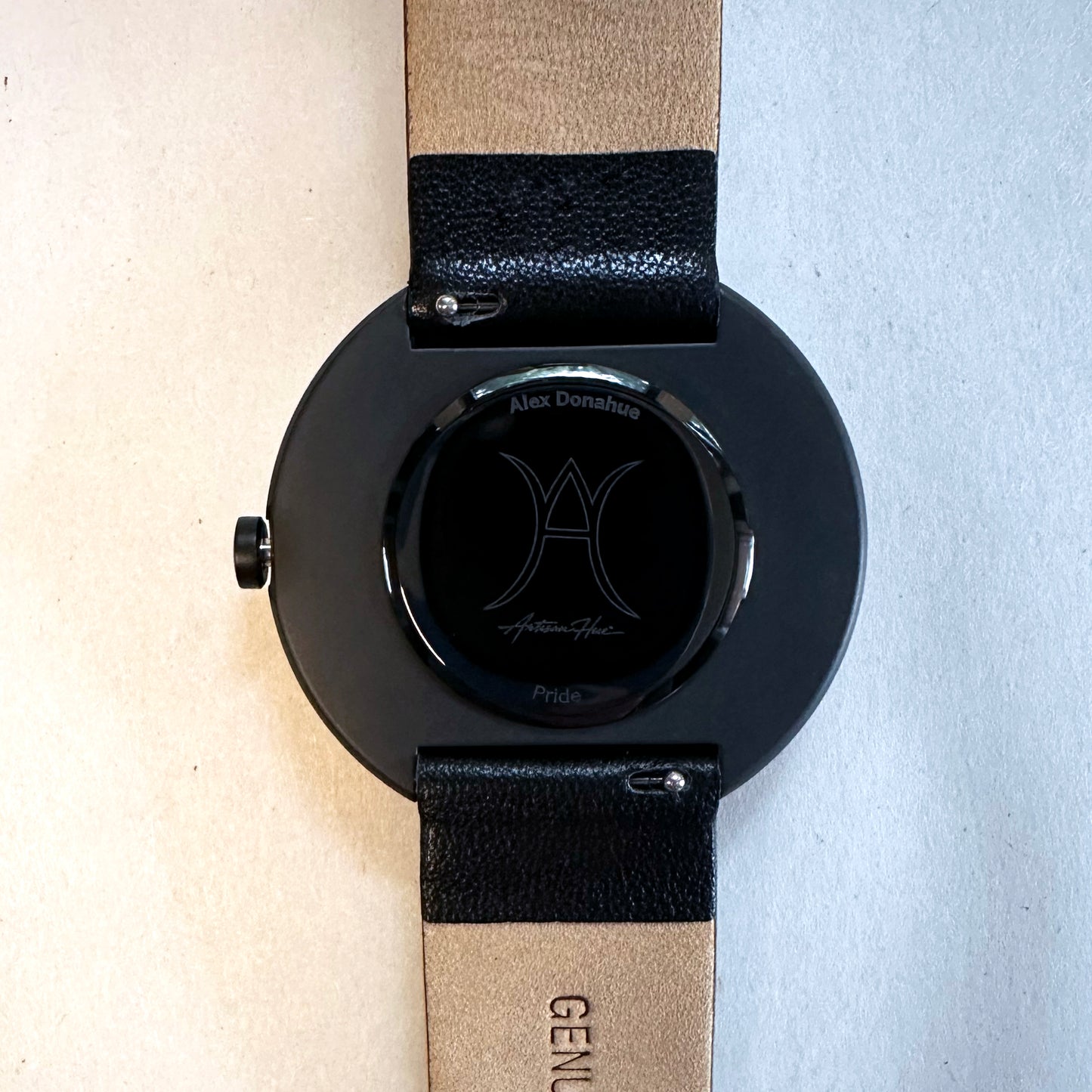 Black watch with a beige strap on a light background