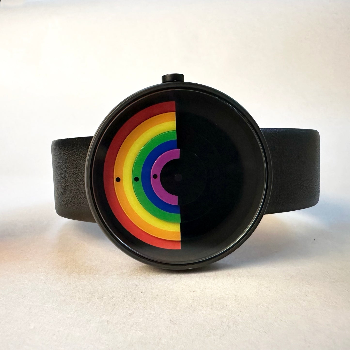 Wristwatch with a black strap and a colorful rainbow design on the face against a white background