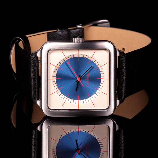 Eddie Wristwatch with stainless steel case and black leather strap, tan and blue face against a black background mad hudson watches