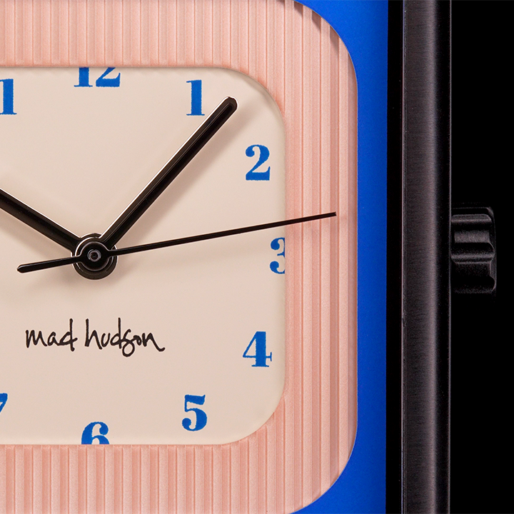 close up Wristwatch with a black leather strap and square case pink blue and tan face steel and black hands blue numbers on a black background The Miami Watch Mad Hudson Watches