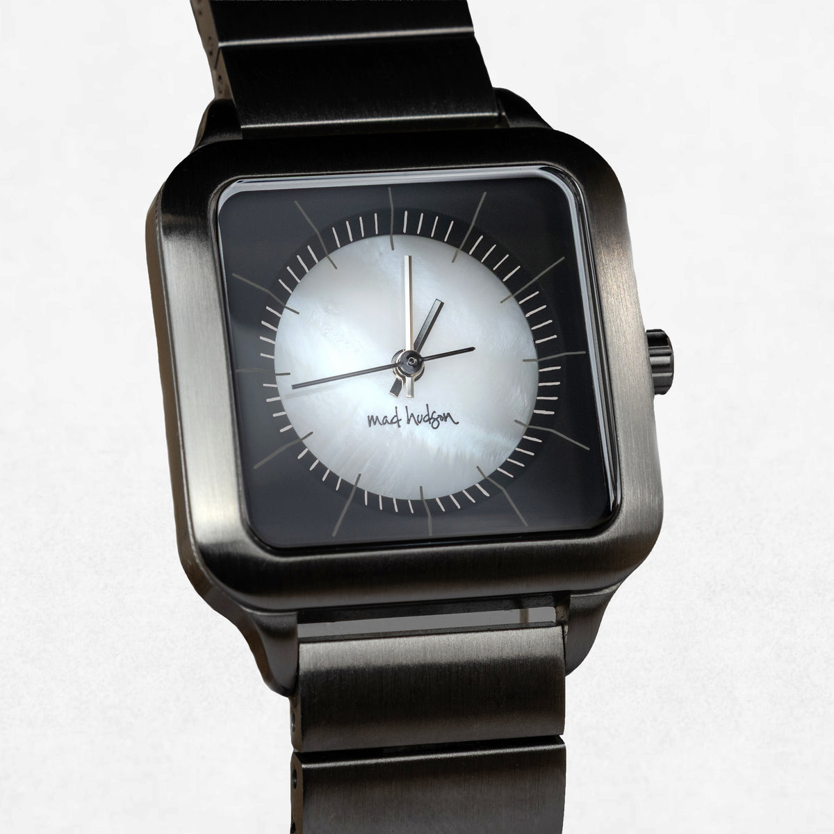 A square-faced wristwatch with a dark gunmetal metal case and link bracelet, featuring a silver-white dial with black hands and markers. The brand name 'matilda hudson' is printed on the dial.