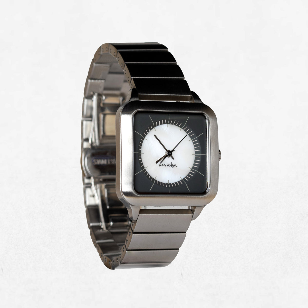 A square analog watch with a silver-toned metal link bracelet, a black bezel, and a white dial with black hands and markings. The brand name 'Kavlioglu' is visible on the dial.