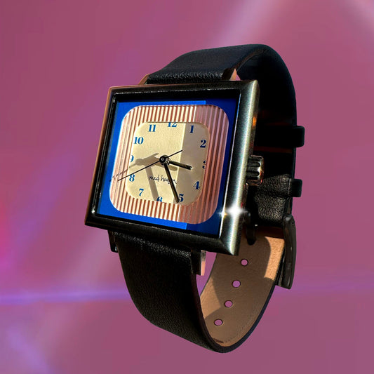 Wristwatch with a black leather strap and square face with blue, pink and tan layers on a pink background The Miami Watch Mad Hudson Watches